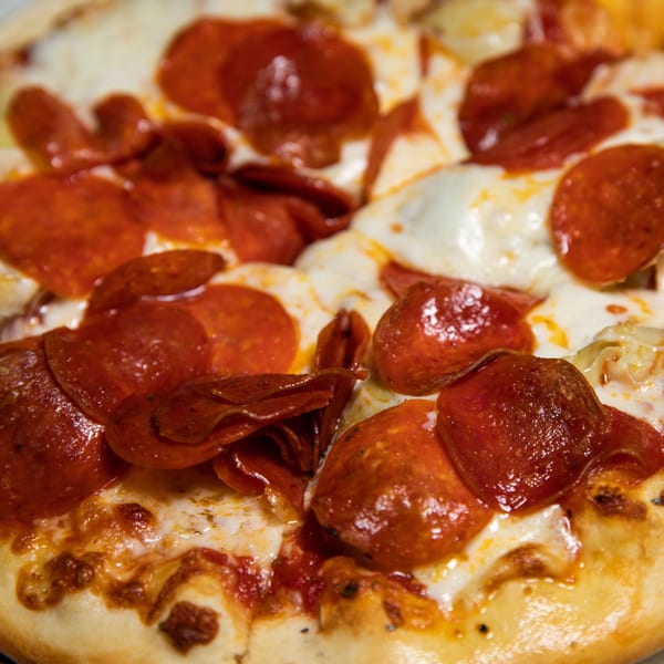 Close-up of a Mama 'n Papa's pepperoni pizza with melted cheese and crispy edges.