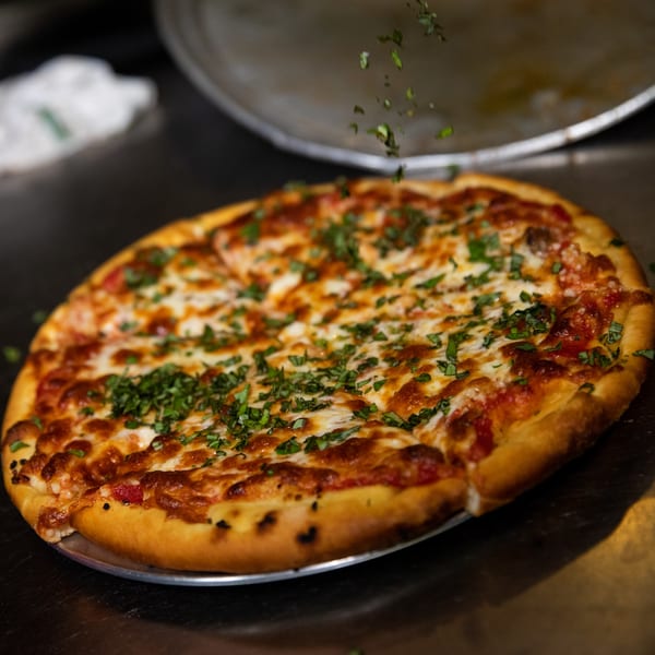 A freshly baked Mama 'n Papa's Pizza Grotto pizza, topped with melted cheese and herbs.